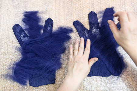 使用湿感觉工艺蓝色梅里诺羊毛用制手套上纤维的工匠迭层图片