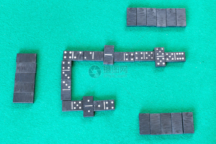 Dominoes棋盘游戏的顶端视图绿色烤桌上有黑瓷砖的牌棋盘游戏图片
