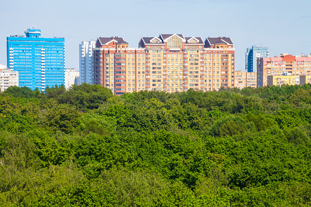 在阳光明媚的夏日照耀着太的绿色城市公园和寓楼上方的绿色城市公园和寓楼图片