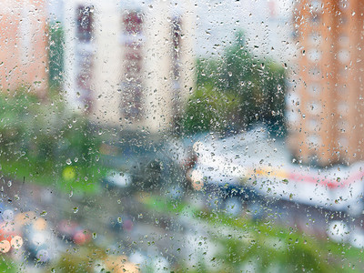 秋天雨背景的家用窗户玻璃上的雨滴和模糊街道上高清图片