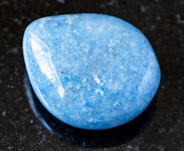 以巴西黑色花岗岩背景的巴西黑花岗岩采样的蓝色Aventurine宝石图片