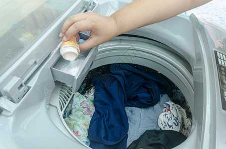 湿的家务机器在洗衣中用手填涤剂图片