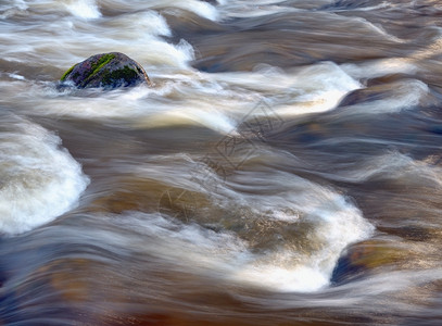 冲一种苔藓河中涌水巨石背景图片