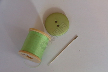 阀芯为了衣服用于缝纫针和绿色按钮的线卷轴图片