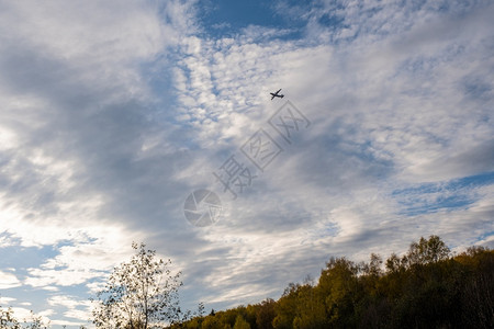 在秋天的森林上与美丽的云天空对抗大飞机休眠超过航班一种图片
