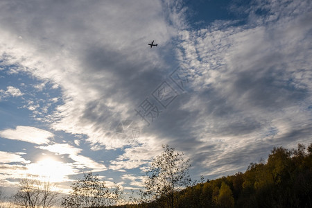 航空在秋天的森林上与美丽的云天空对抗大飞机休眠轮廓行图片