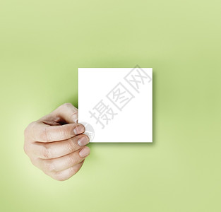 信息一只手在绿色背景上拿着空白纸条色的笔记背景图片