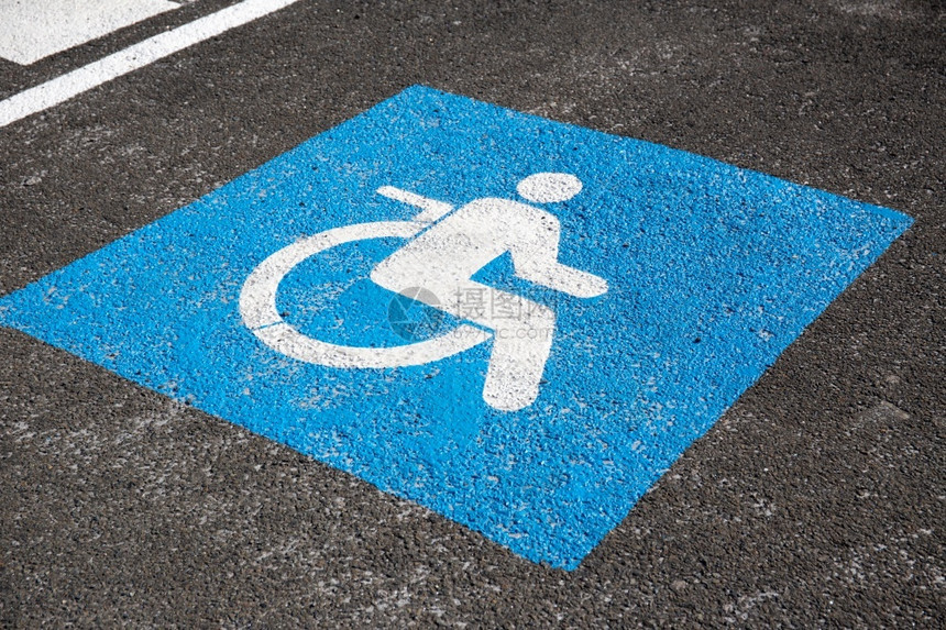 蓝色的失能沥青上涂有残疾人符号的标牌象征图片