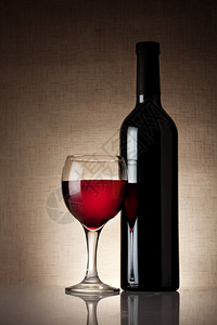 一杯红葡萄酒瓶子在薄饼背景上玻璃木制的反射图片