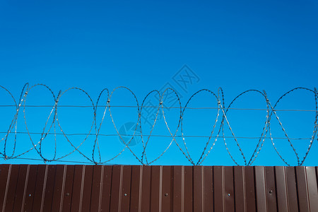 金属丝明亮的蓝色天空背景的棕金属栅栏和铁丝网白色的背景图片