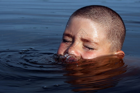 湿的活动男孩在池塘中游玩开始泡在水面上头部的顶是可见眼睛眨孩子图片