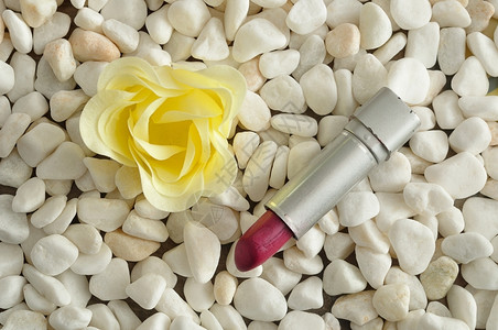 戳化妆品魅力用白花在石子上展示的红口唇膏图片