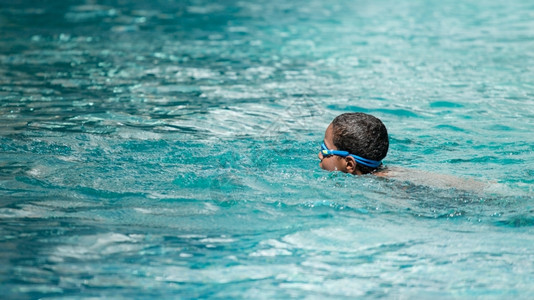 一个小男孩在游泳池里游泳图片