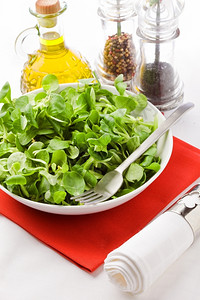 红色餐巾上带叉子和橄榄油的缬草沙拉照片素食主义者食物图片
