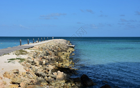 加勒比海沿向阿鲁巴蓝热带水域延伸的岩石堤坝海岸图片