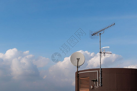 网络蓝色的屋顶上安装电视天线和舌状用云层抵挡蓝色天空联系图片