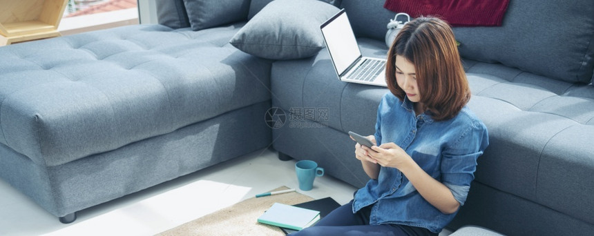 年轻女子靠在沙发边上玩手机图片