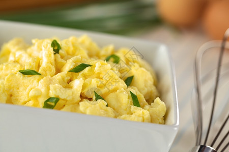 碗里有绿洋葱的炒鸡蛋另一边有打手选择焦点三分之一在碗里小吃早餐炒的背景图片