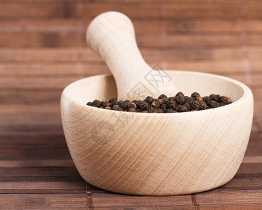 黑色的香料杵木制砂浆中的胡椒粒木制背景中的砂浆胡椒粒背景图片