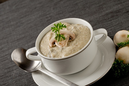 照片美味的蘑菇奶油汤和灰毛巾上的欧斯利香菜门户14勺子图片