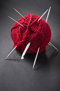 红色的深背景中羊毛球和织针工艺自然图片