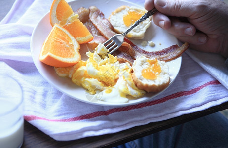 盘子玻璃男人吃美味的早餐培根炒鸡蛋饼干加果酱和橙子牛奶图片