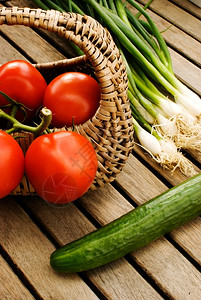 新鲜蔬菜西红茄黄瓜和绿洋葱在木制桌边的篮子中生木制桌子图片