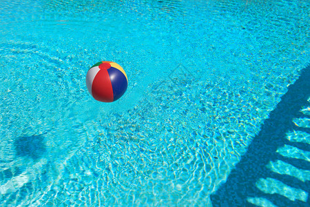 游泳池水中漂浮在的充气多彩海滩球图片