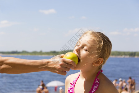 女孩从母亲手中咬苹果的照片图片