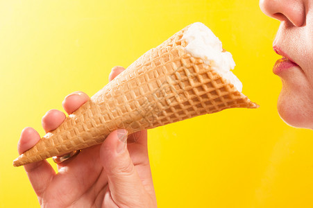 圣代颜色胡扯在黄背景上向女嘴唇的冰淇淋甜筒图片
