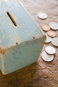 收藏金融的木制表面用硬币装在木制表面的旧钱箱的背景图片