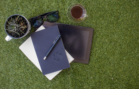 使用平板笔记本移动和草坪上一杯茶的零干劳动区绿色放松桌子背景图片