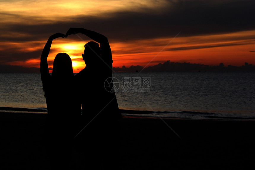 日落夏天在海滩上浪漫蜜月情侣的周光美丽日出背景在海滩上轮廓图片