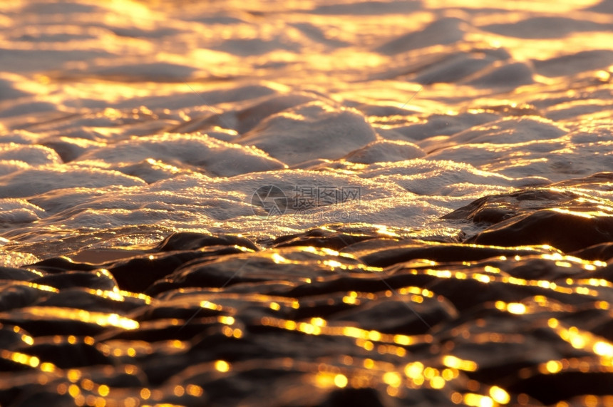 细节自然海滩日落时太阳在拜萨尔特岩石上反射图片