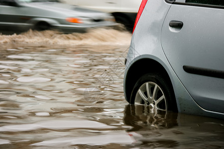停車處安全危险的白天下雨后在水淹路上停车的灰色汽高清图片
