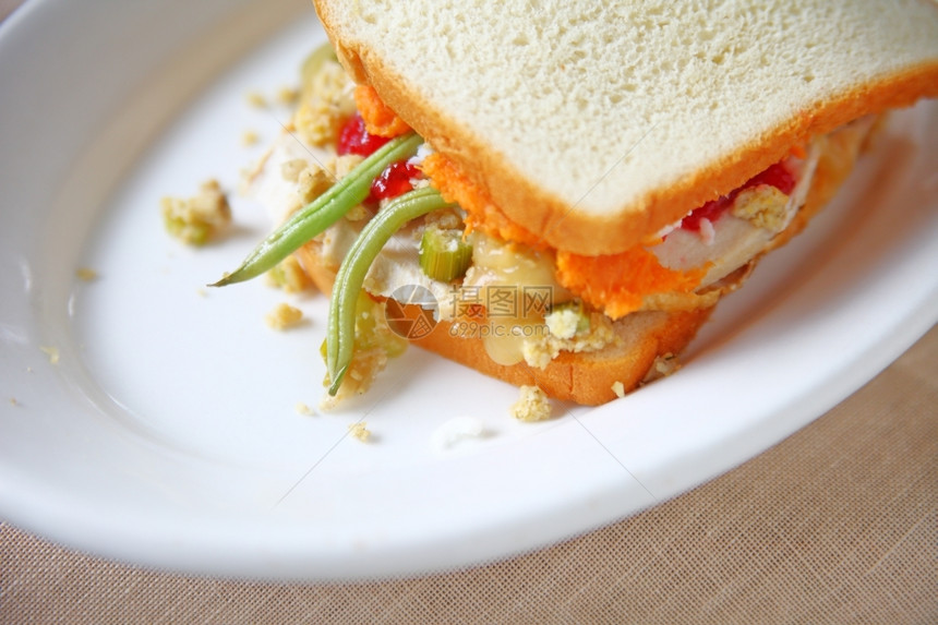 白色的关闭面包上感恩节剩菜的火鸡三明治豆子土图片