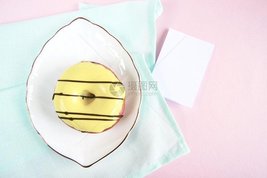 奶油盘子蓝色的粉红背景模型卡片旁边是蓝棉巾和白瓷板以黄甜圈叶形状的白瓷板图片