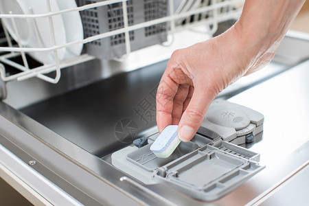 近距离将洗涤剂板放入dishwater的妇女洗碗机水图片