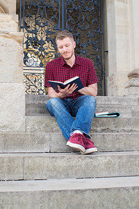 男大学生在楼外的台阶和阅读上坐着教育男人图片