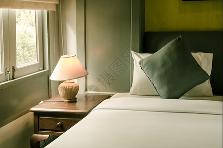 寝具音调住宅床上的枕头和柜上的灯暖色调图片