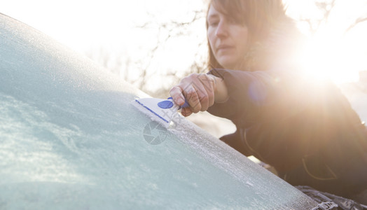 水平的汽车挡风玻璃中的妇女排冰霜刮刀图片