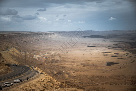宽的以色列内盖夫沙漠公路上的汽车以色列内盖夫沙漠山陨石坑图片
