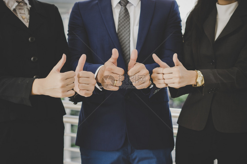 站在办公室前成功的商务团队竖起大拇指站在办公室前成功的商务团队支持公司的行政人员图片