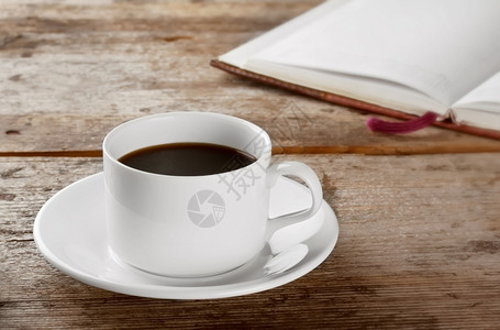 黑色的茶点气泡白圆杯黑咖啡在木桌和一本书图片