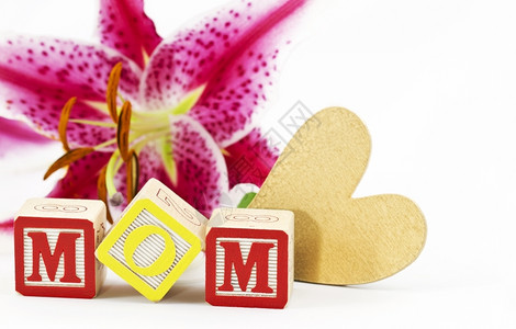 拼写MOM的金心和字母缩写块放在白色背景下一朵百丽花开前衷心黄色的白图片