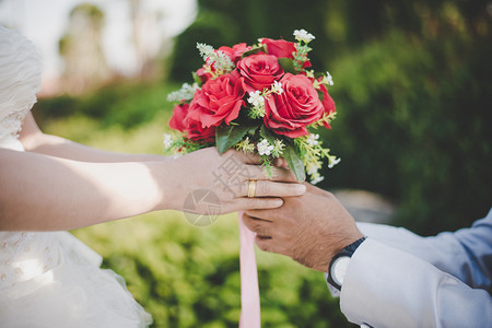 漂亮的婚姻人们新郎用自然背景给新娘送花束给新娘图片