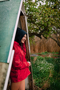 穿着红雨衣的微笑女孩躲在雨中避女士夏天庇护所图片