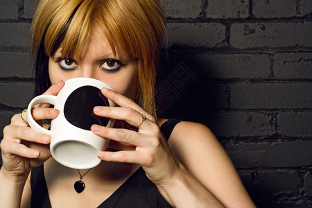 女喝咖啡与城市馆黑砖墙对冲盯早餐饮料图片