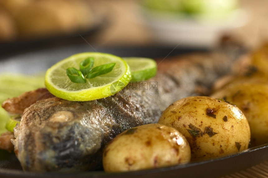 有石灰片和马铃薯的炸鳟鱼有石油汁中的柠檬和土豆有选择的重点集中注意鱼面上的石灰片前香菜蔬图片