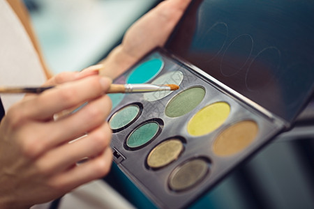 化妆艺术家拿着彩色双眼草和刷子的调色盘关上女士美丽的图片